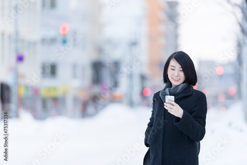 冬の街角でスマートフォンを持つ女性 Stock Photo Adobe Stock