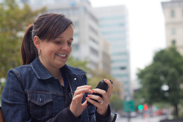 Wall Mural - Woman texting with her smart phone outside in the city