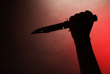 Female Hand Holding Knife On Red Background