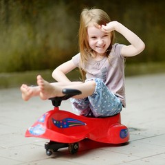 Wall Mural - Adorable little girl driving a toy car