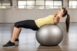 © imacture - Young woman doing abdominal on a exercise ball