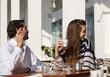 © mimagephotos - young couple sitting at outdoor cafe asking for the bill