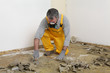 © sima - Worker with mask cleaning floor with putty knife, renovation