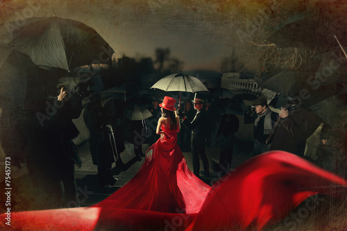 Fotografie, Obraz Woman in red dress on carpet. photo of paparazzi back.