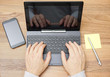 © Bacho Foto - Top view of man hands working on laptop or tablet pc on wooden d