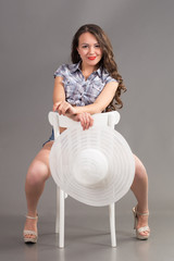 Wall Mural - brunette with long hair sits on chair with white summer hat