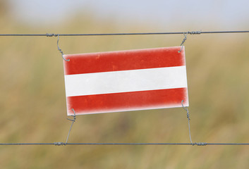 Wall Mural - Border fence - Old plastic sign with a flag