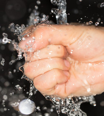 Wall Mural - hand in water on a black background