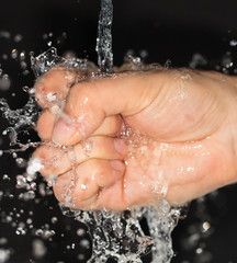 Wall Mural - hand in water on a black background