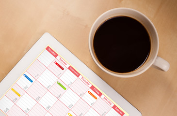 Wall Mural - tablet pc showing calendar on screen with a cup of coffee on a d