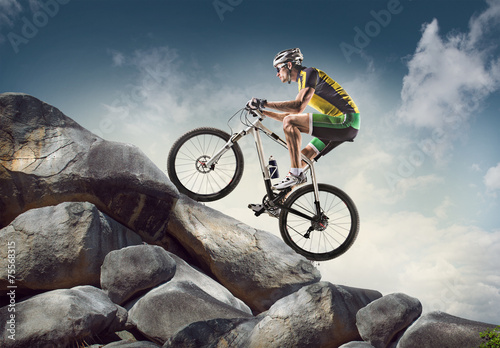 Obraz w ramie Sport background. Cyclist climbing on a rock.