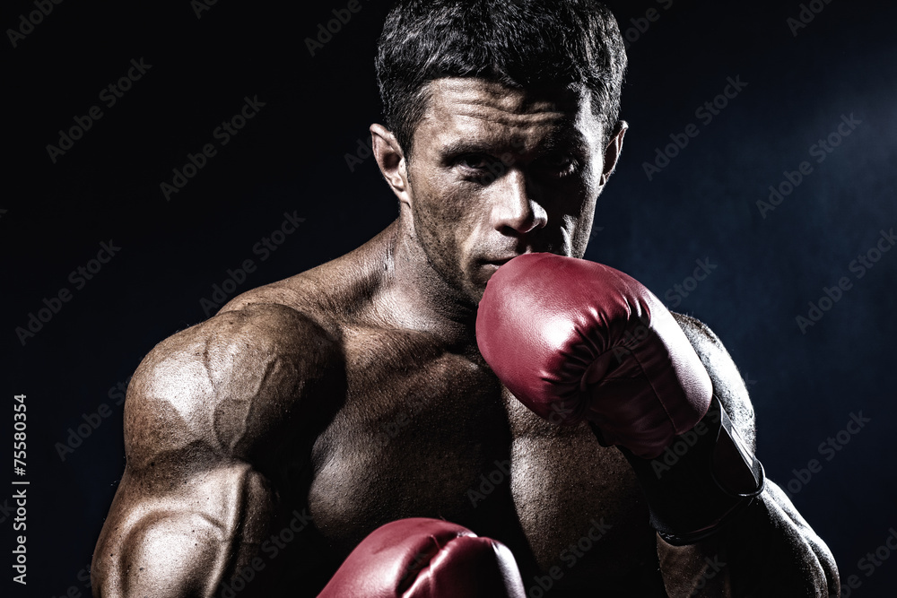Foto Strong muscular boxer in red boxing gloves. A man in a boxing st