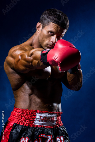 Leinwand Poster Strong muscular boxer in red boxing gloves. A man in a boxer's s