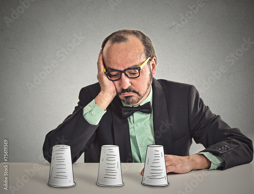 Fotografie, Obraz Man with glasses sitting at desk playing a conjuring trick game