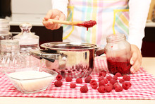 Woman Cooking Raspberry Jam In Kitchen