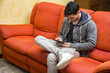 © theartofphoto - Handsome young man at home reading with ebook reader