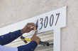 House Painter Contractor Nails Address Numbers to House Facade