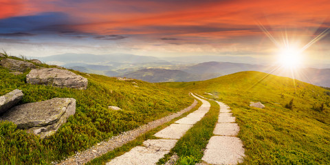 Wall Mural - road on a hillside near mountain peak at sunset