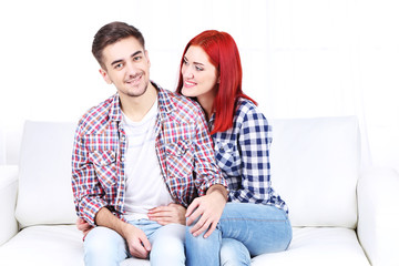 Poster - Young couple sitting together in sofa in room