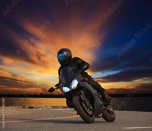 Naklejka dekoracyjna young man riding big bike motorcycle leaning curve on asphalt hi