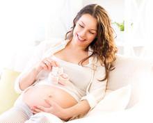 Pregnant Happy Woman Holding Blue Baby Shoes In Her Hands
