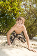 © travelview - happy young boy is digging in the sand of the beach
