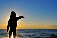 Silhouette Of A Boy Pointing Out The Sea