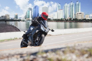 young man riding big bike motorcycle on city road against urban