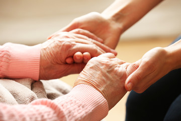 Wall Mural - Old and young holding hands on light background