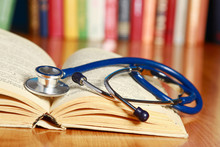 A Stethoscope Is Lying With A Book On The Desk Against Books