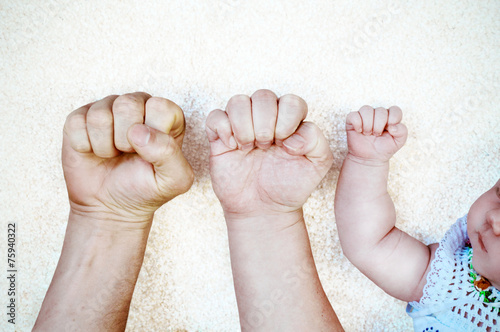 Young couple and their baby´s fists in one line. Poster