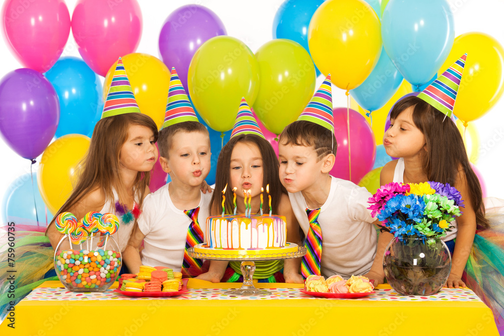 Kids celebrating birthday party and blowing candles on cake - obrazy, fototapety, plakaty 