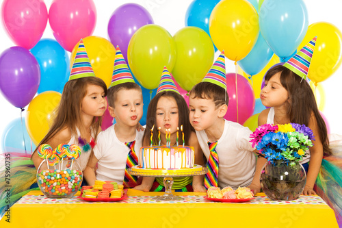 Fotografía Kids celebrating birthday party and blowing candles on cake