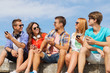 © Syda Productions - group of smiling friends with smartphones outdoors