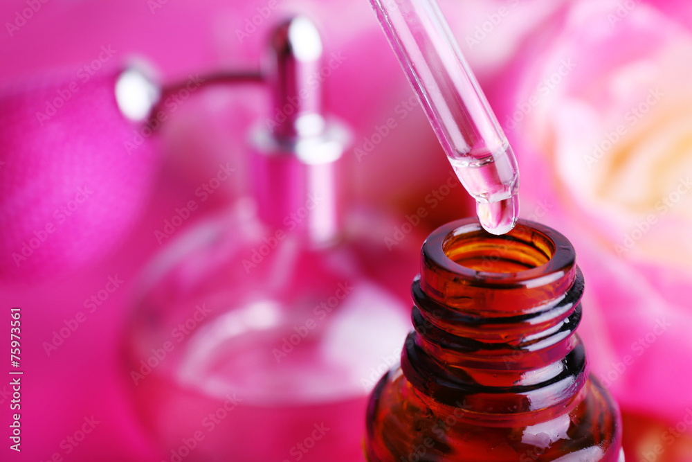 Dropper bottle of perfume with peony on pink background