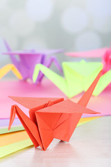 Wall Mural - Origami cranes on wooden table, on light background