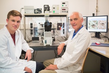 Wall Mural - biochemist using large microscope and computer with student