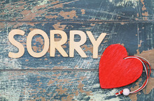 Sorry Written With Wooden Letters On Rustic Wood, And Red Heart