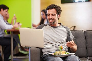 Wall Mural - Man Sitting On Sofa And Eating Lunch In Design Studio