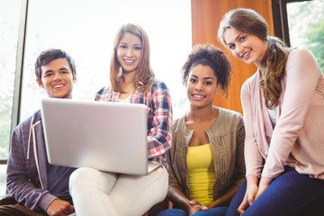 Poster - Smiling students sitting on couch using laptop