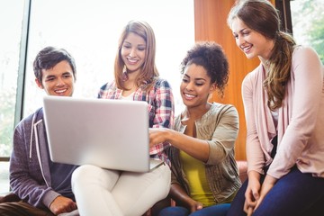 Poster - smiling students sitting on couch using laptop
