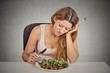 © pathdoc - sad displeased young woman eating salad grey wall background