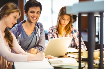 Poster - Student looking at camera while studying with classmates