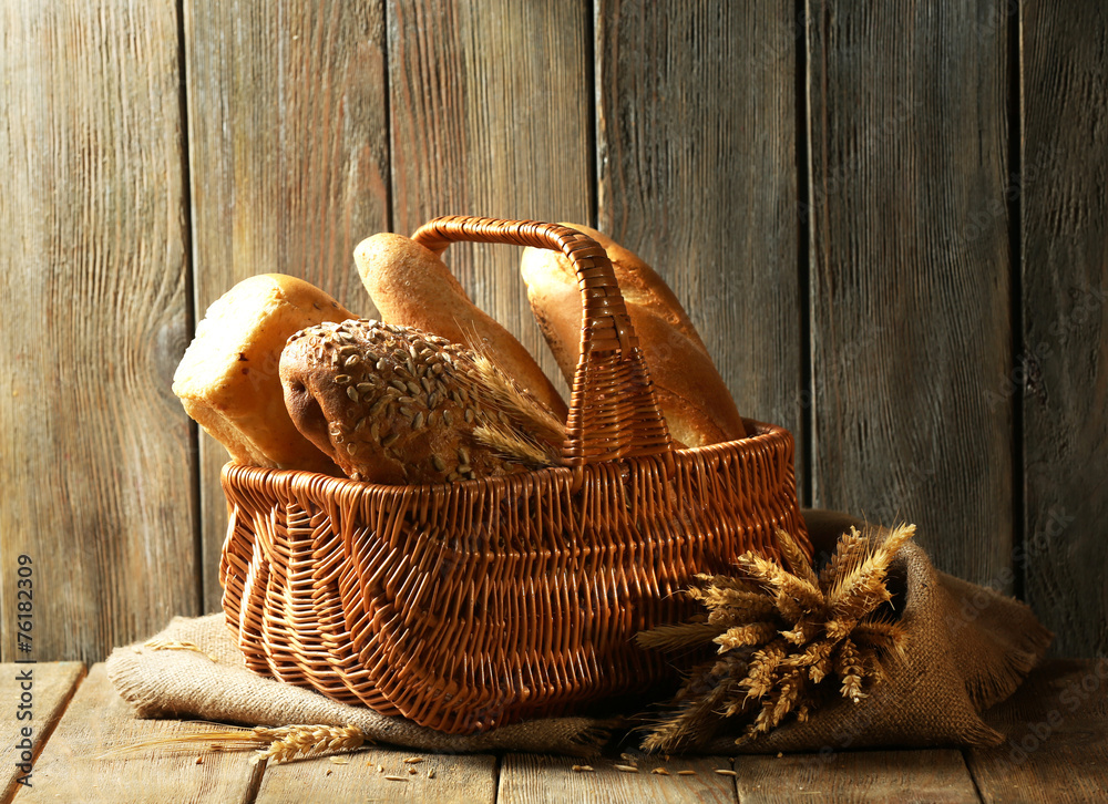 Different bread in wicker basket on table on wooden background