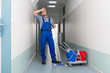Tired Male Worker Cleaning Office Corridor