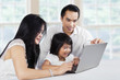 © Creativa Images - Happy family browsing internet with laptop