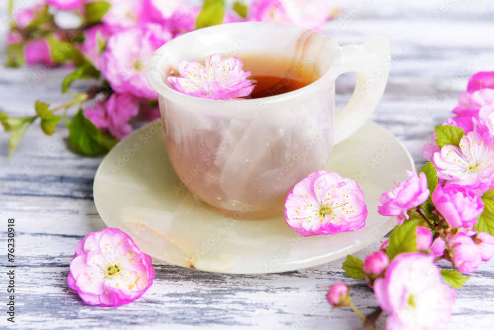 Beautiful fruit blossom with cup of tea on table close-up