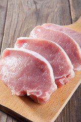 Wall Mural - Raw pork chops on wooden cutting board.