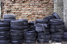 Old Used Tires Stocked For Recycling At Red Brick Wall