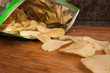 Potato chips coming out of a bag onto a wood board